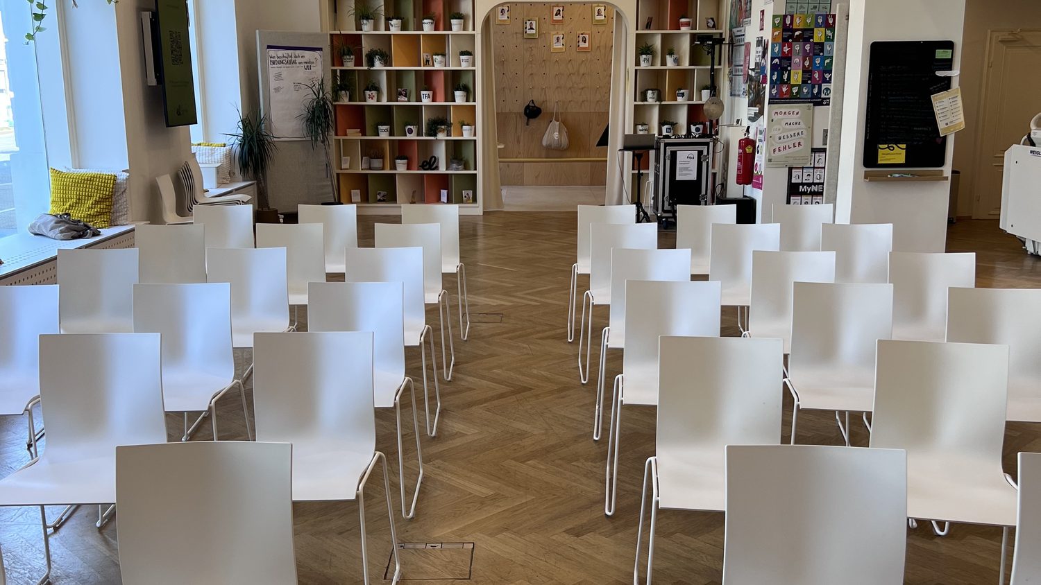Heller Veranstaltungsraum von Workspace mit Stuhlreihen und offenen Regalen